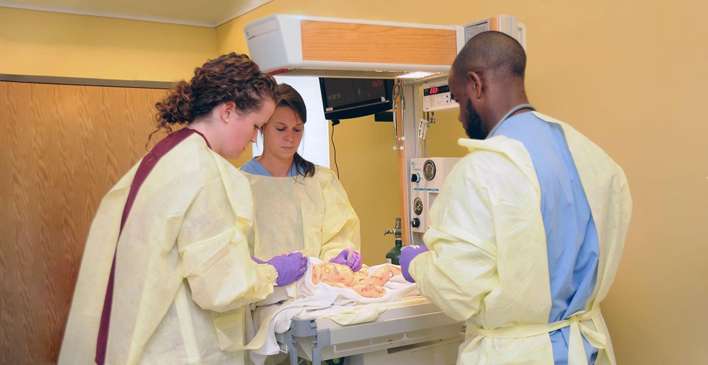 Salisbury University students in the medical simulation (sim) center study a simulated baby