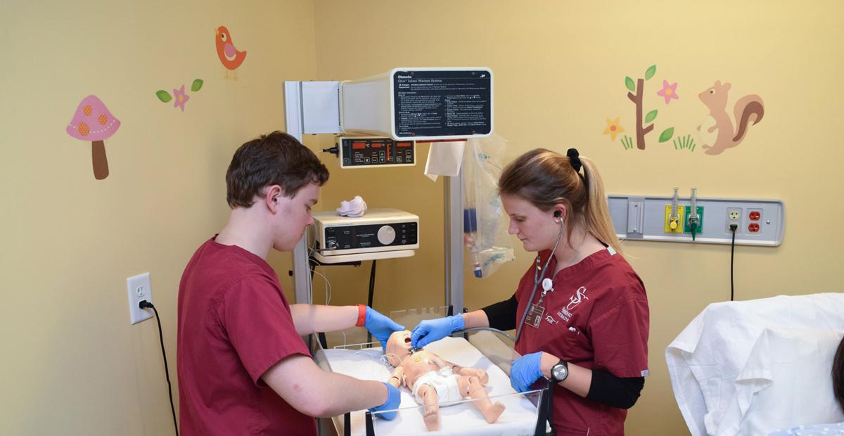 两个护理学生在SIM中心照顾一个假婴儿病人