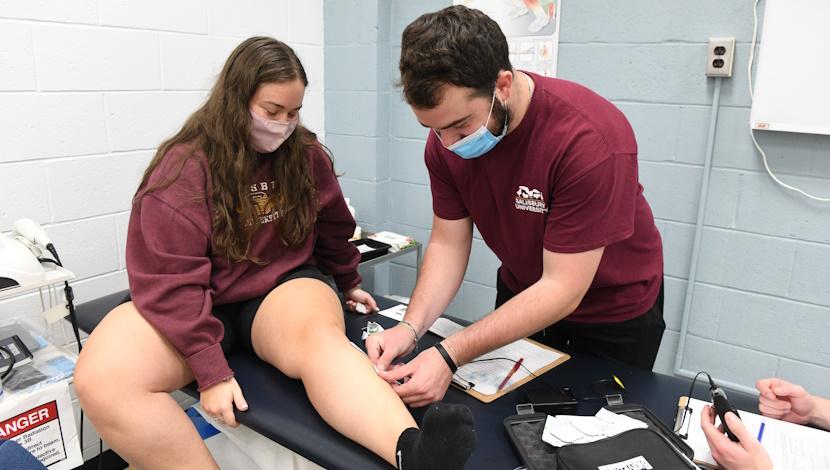 Student connecting a monitoring device to a patient 