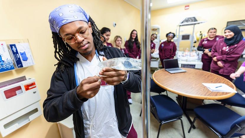 Student adds a bag to an IV holder