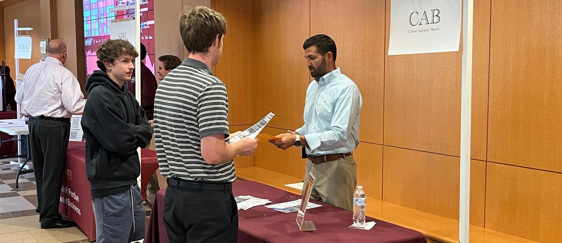 Two Students talk to faculty mentor at a table event