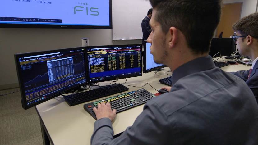 Student at computer looking at stocks ticker