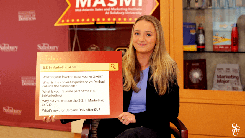 Student holding an FAQ question board