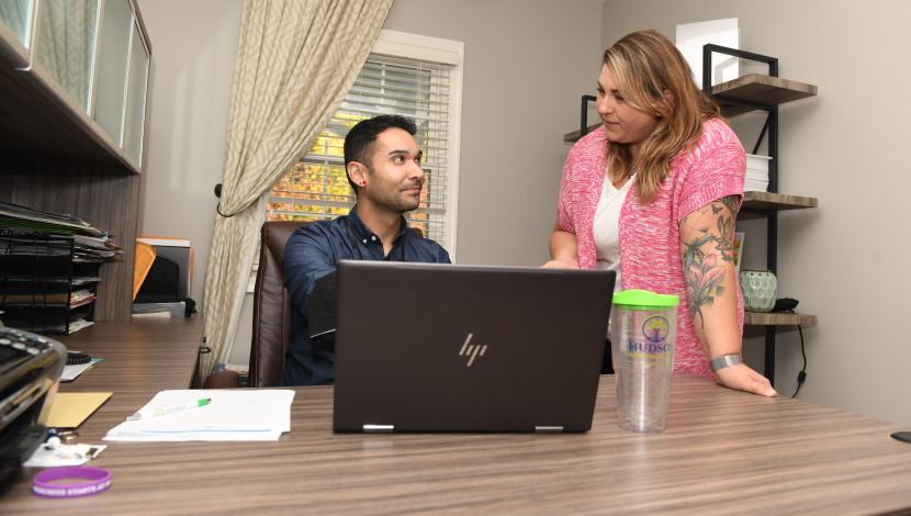 Two people use an discuss over a laptop