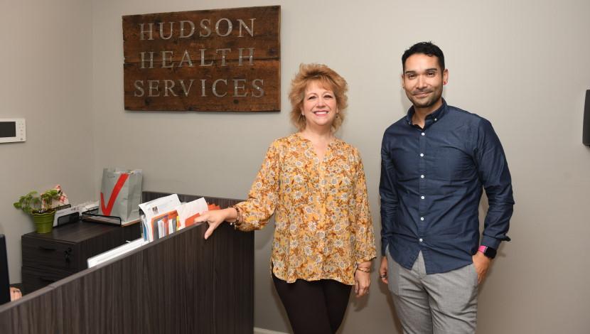 Three people pose at a front desk