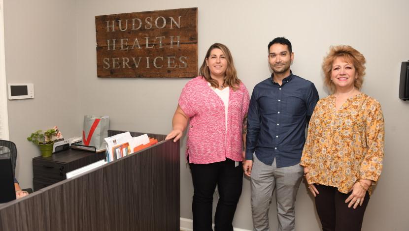Two people pose at a front desk