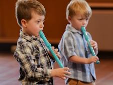 Two very young children play recorders