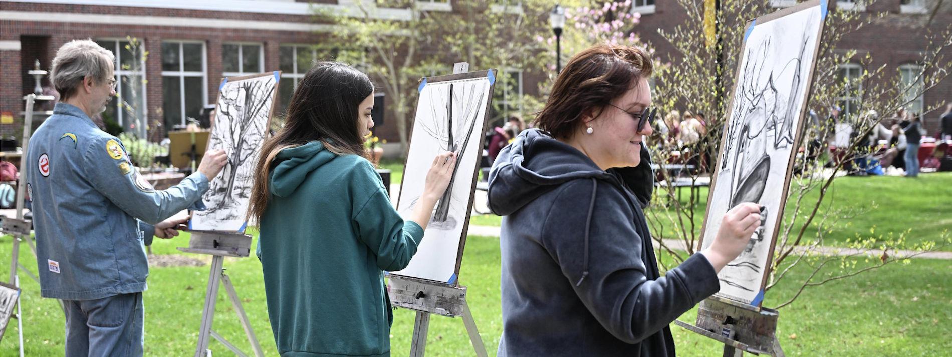 students painting at easels on campus