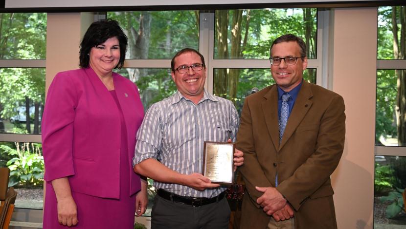 Faculty poses with award and two others
