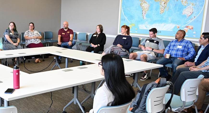 Faculty sit at a large sqaure table for a talk