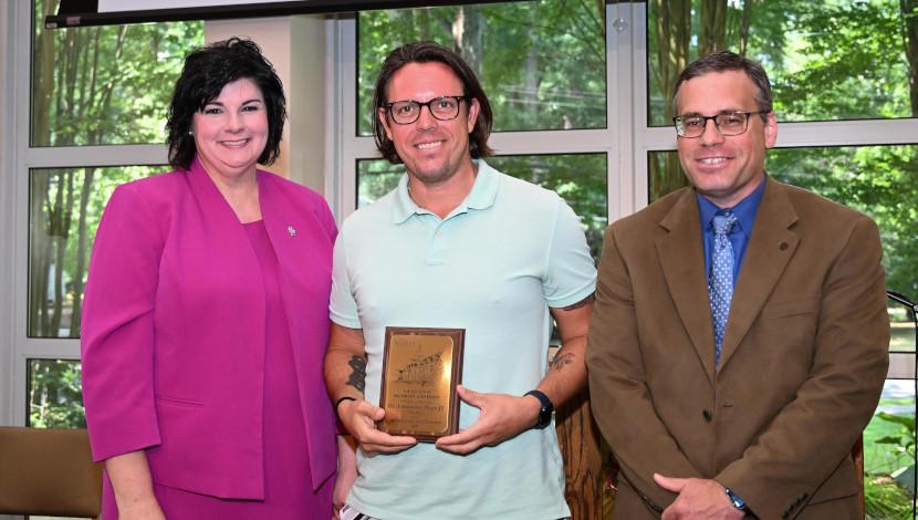 Faculty poses with award and two others