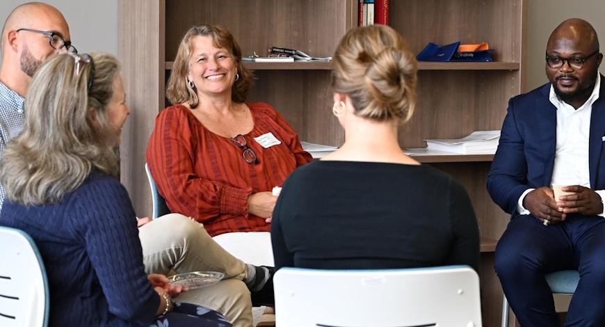 Faculty sit talking in a circle a social event