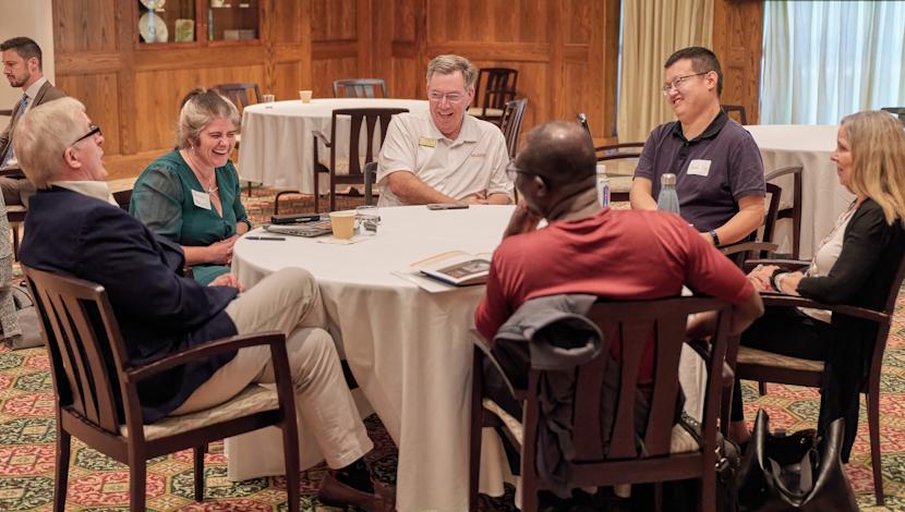 Faculty sit and talk at a circle table