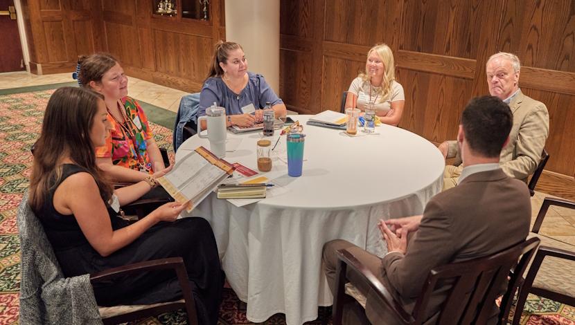 Faculty sit a circle tables during an event