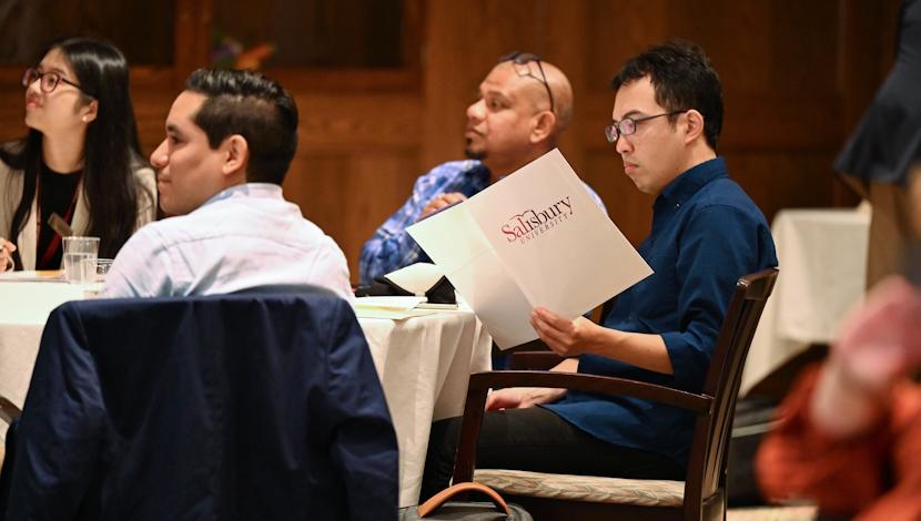 Faculty sit and stand while attending an event