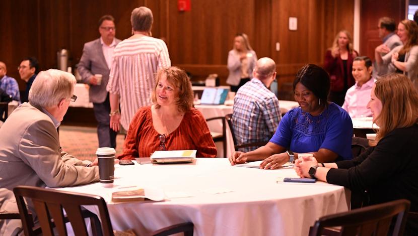 Faculty sit a circle tables during an event