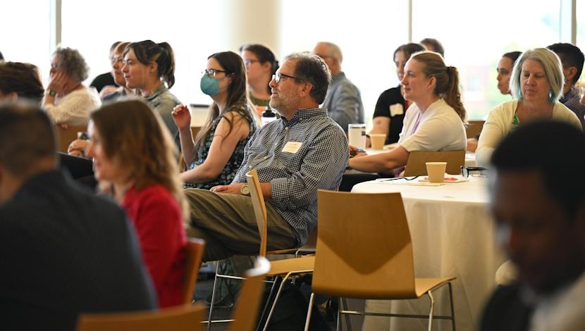 Faculty listen to speaker at a table