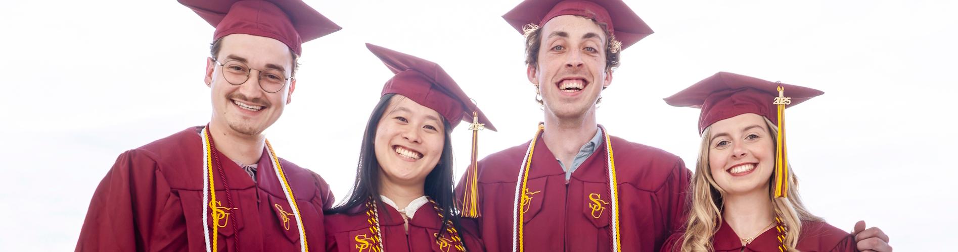4 students in a graduation atire pose for photo
