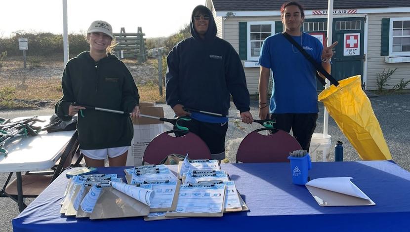 Three students working a recycling event table