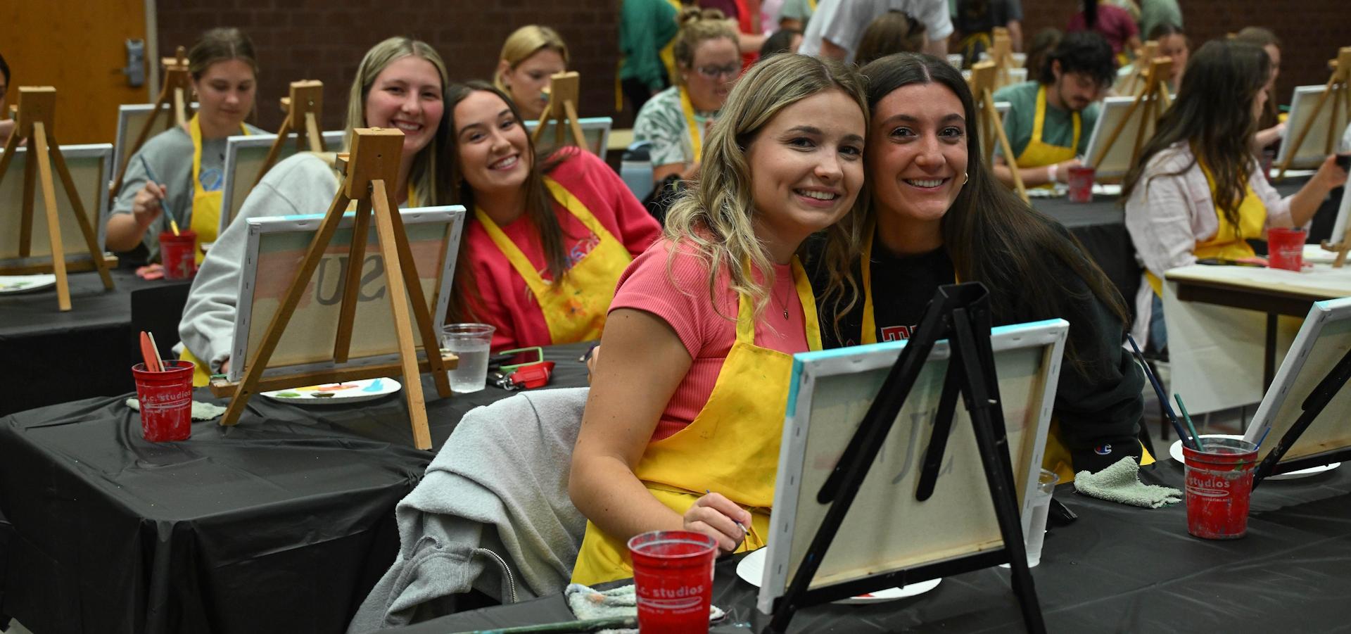 Senior Send off event that shows pairs of students painting on individual canvas