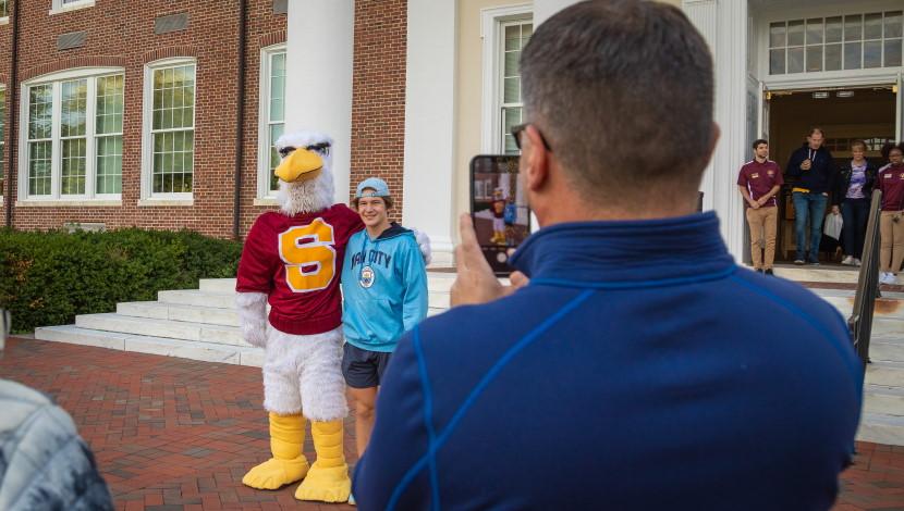 Student takes picture with Sammy outside HH