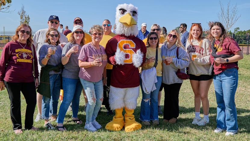 Group photo of alumni and family with Sammy the Sea Gull