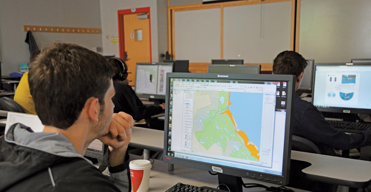A student of the Salisbury University online masters program in GIS looks at maps on a computer.