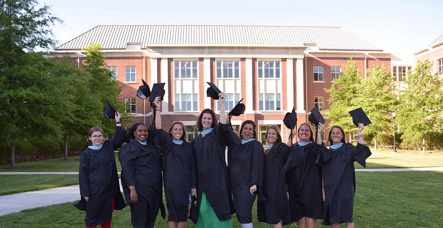 master's in education students holding grad caps