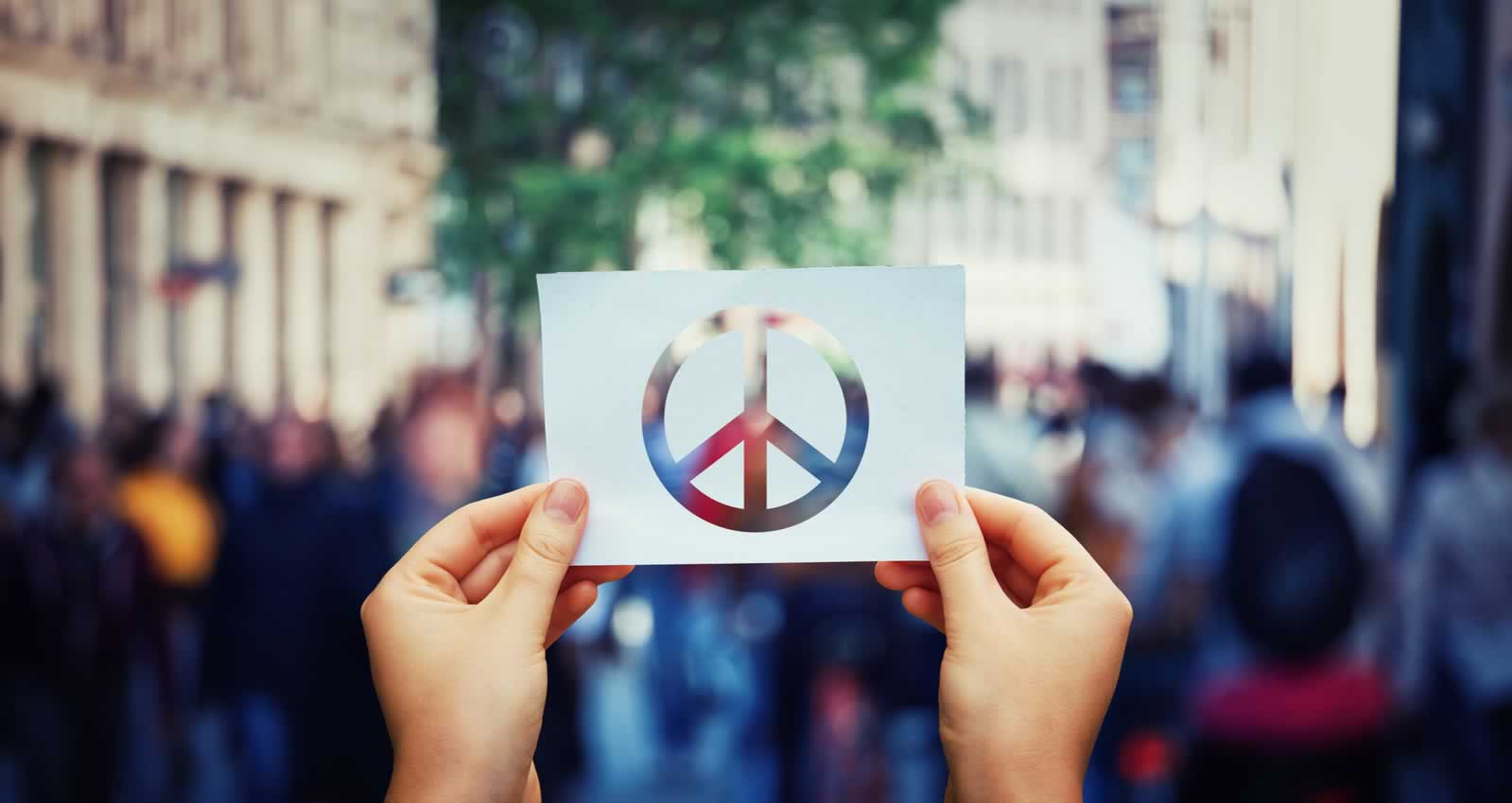 Conflict resolution student's hands holding up peace sign on paper