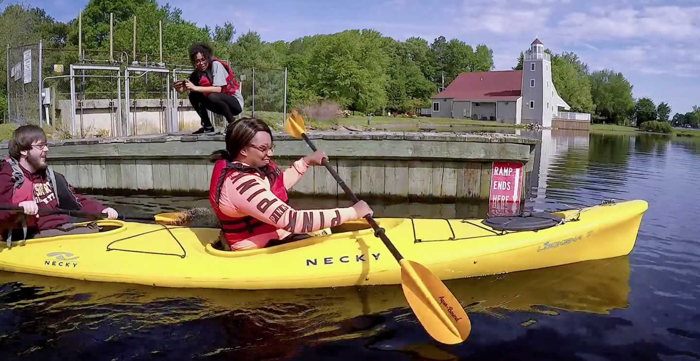 students paddling away from a dock in a kayak