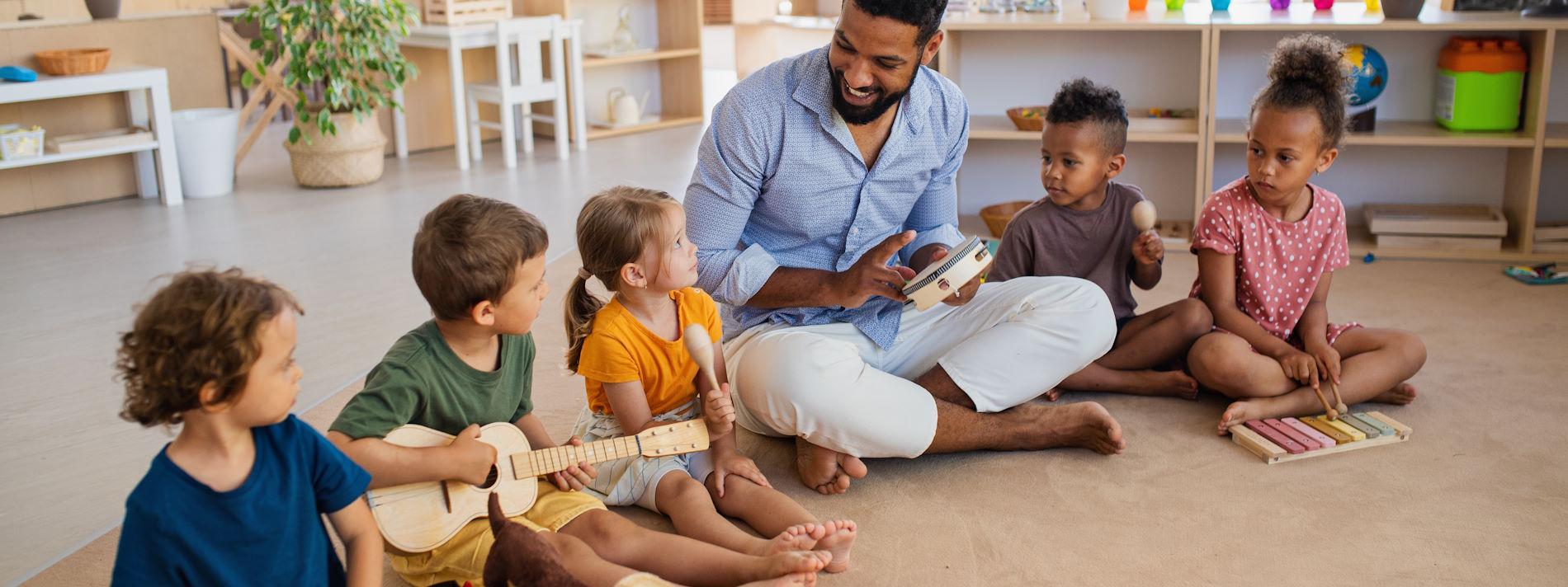 Children with music instructor sitting on the floor with instruments