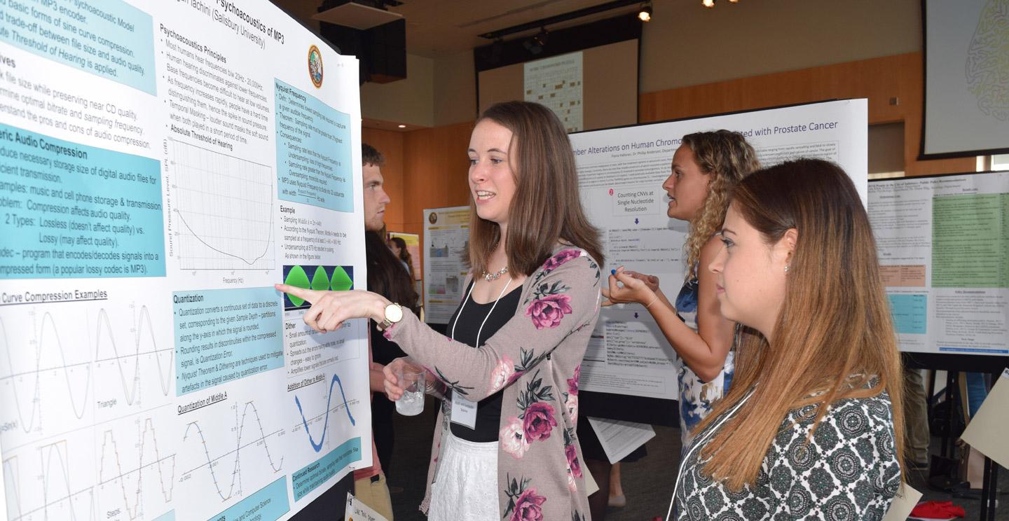 student explaining her undergraduate research poster to a peer
