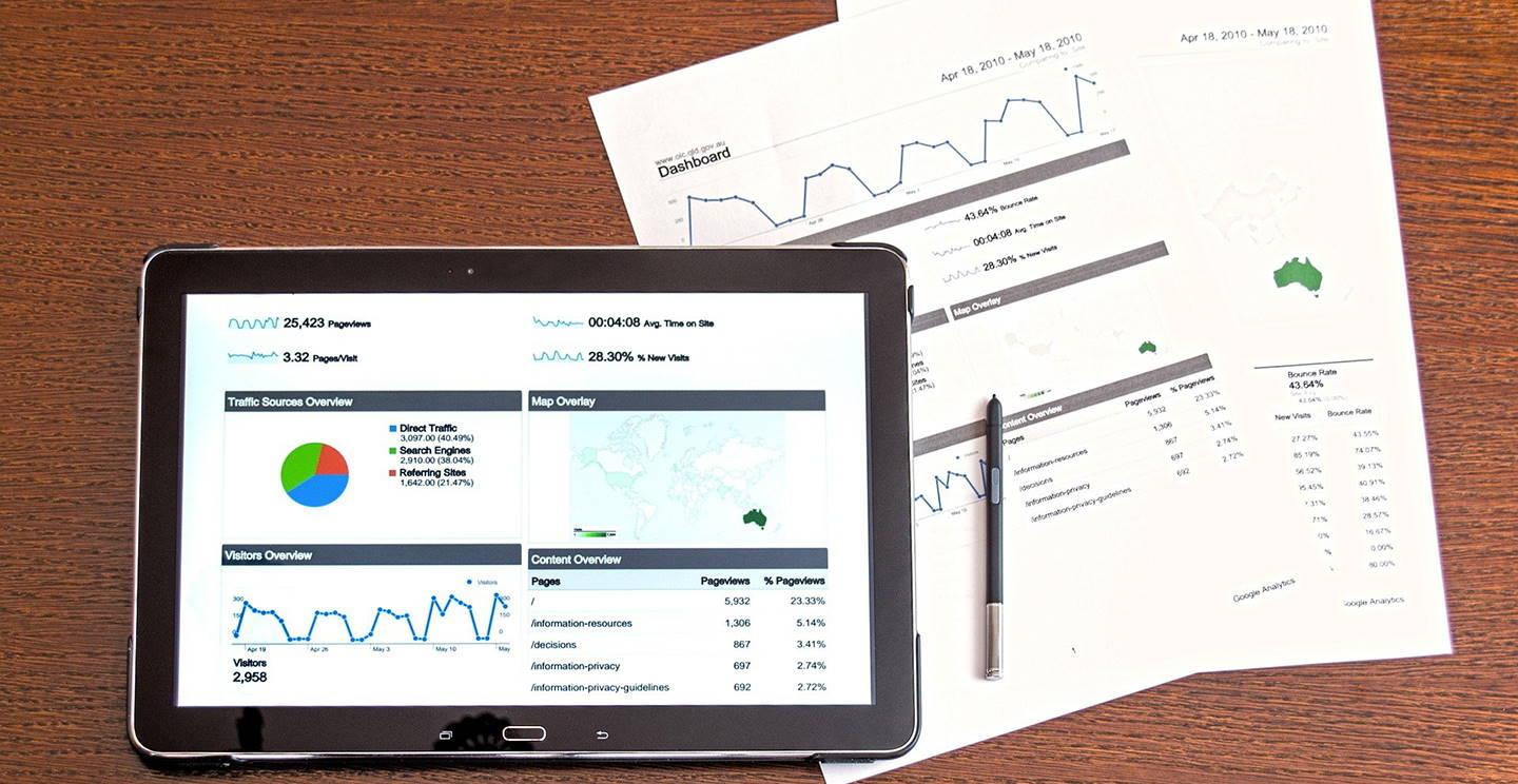 Tablet with charts on desk next to paperwork