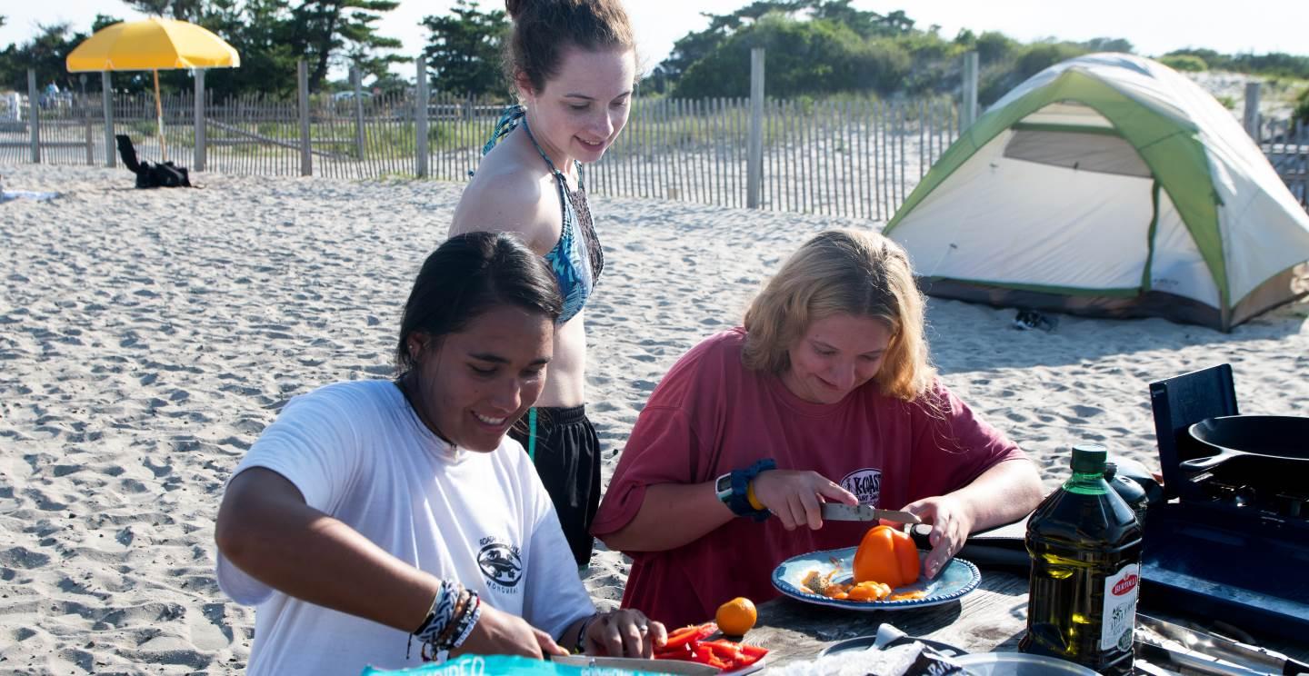 Students cooking on a table at the beach