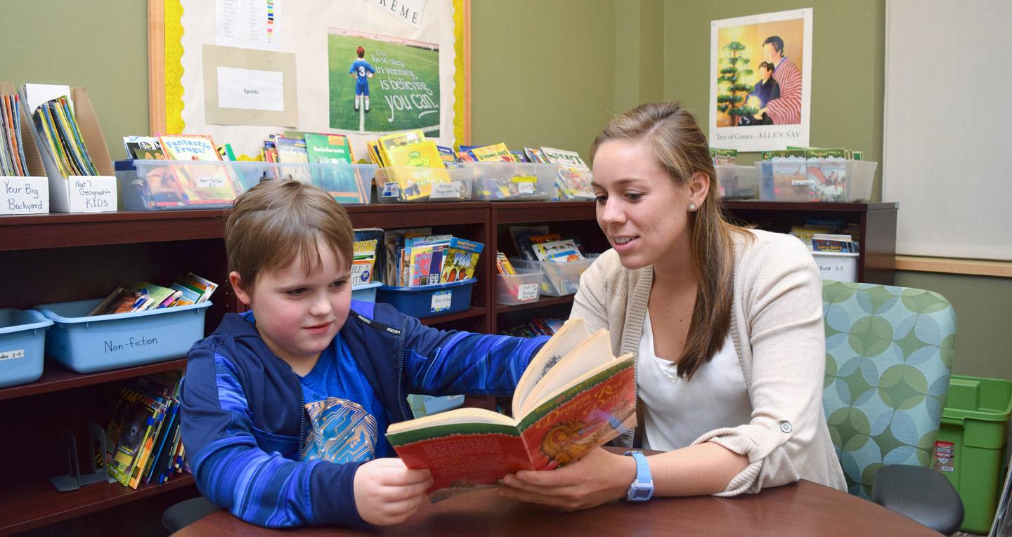 student of Salisbury University's Elementary Education with Dual Certification in Early Childhood Education helping young boy read