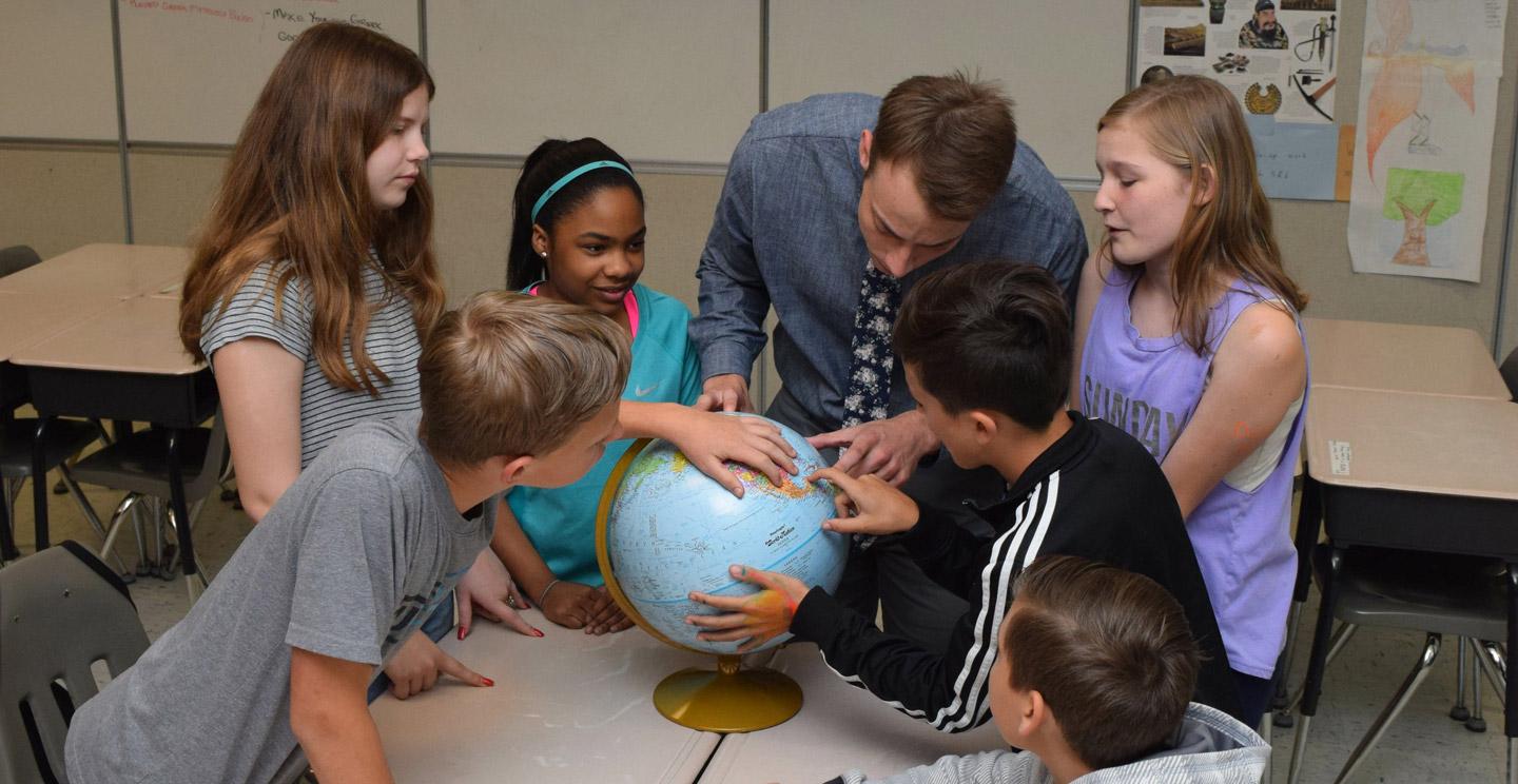 student teacher showing several students a globe
