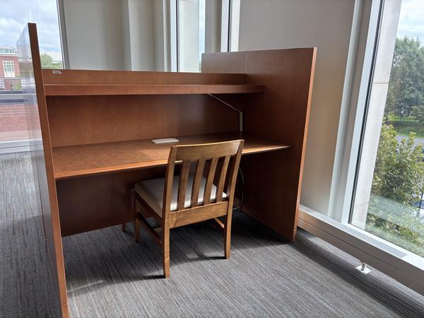Study carrel with a single chair. The carrel is a partially-enclosed desk with a shelf mounted above the desktop.