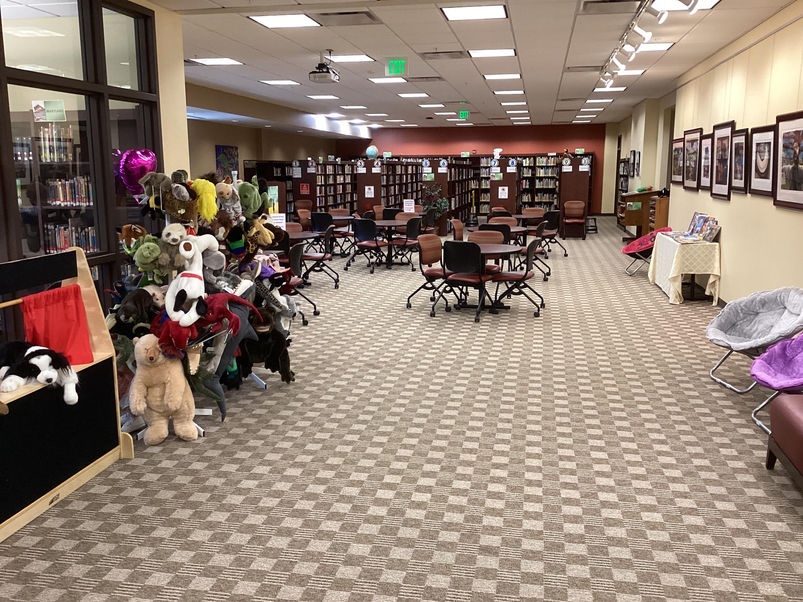 Interior photo of the CRC showing tables, seating, bookshelves and a collection of puppets.