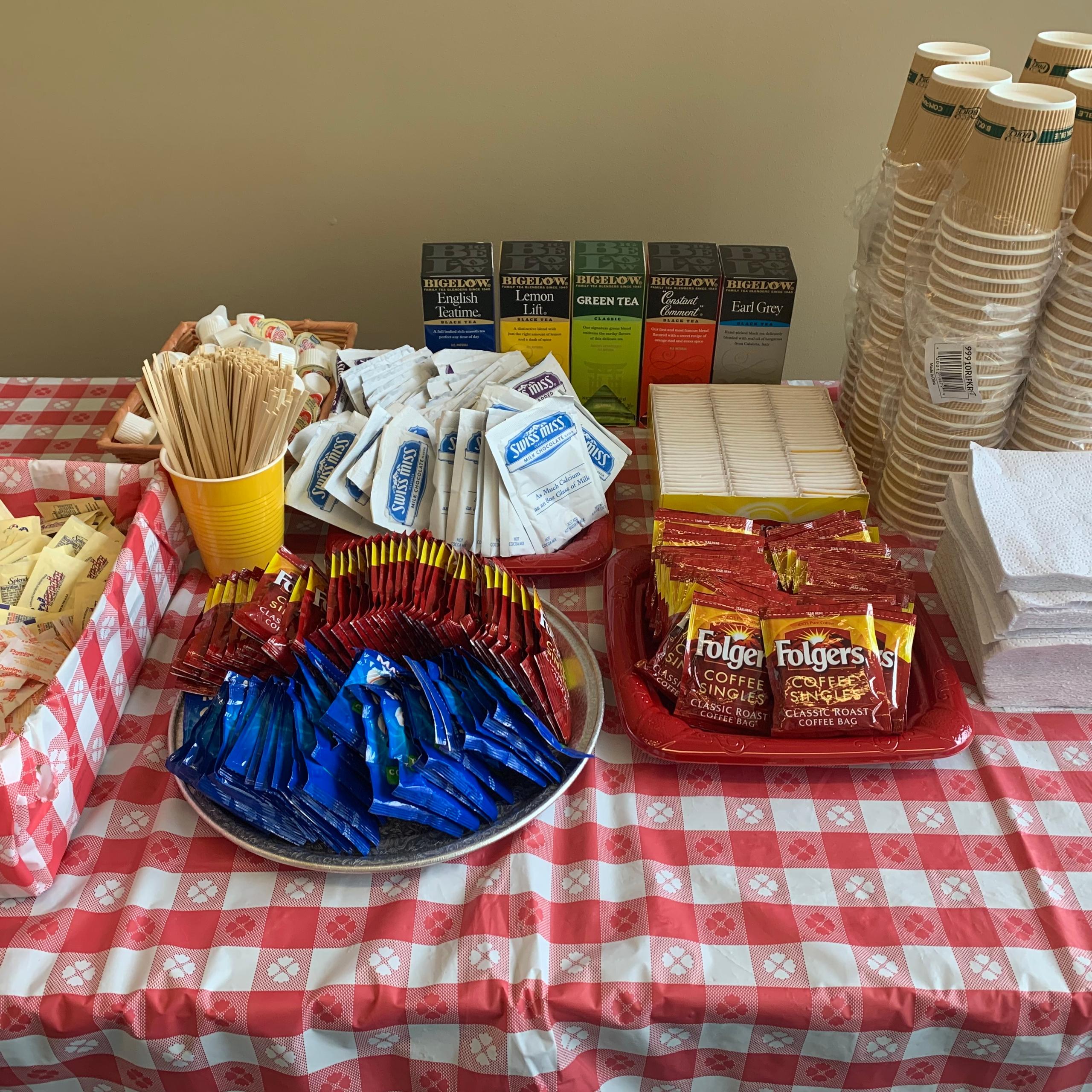 Coffee, hot chocolage, tea bags, and beverage cups on a table.