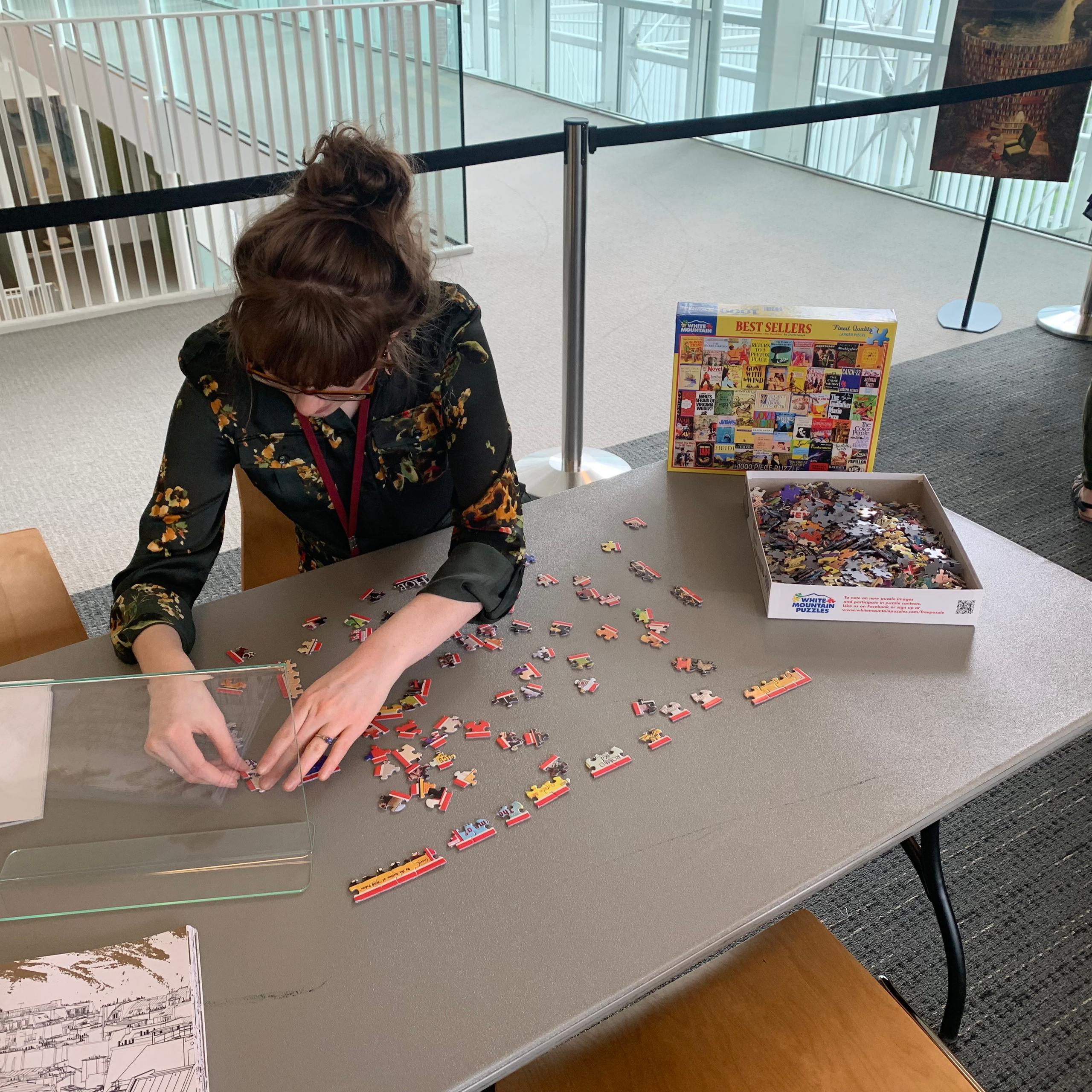 An SU Librarian working on a puzzle at a table.