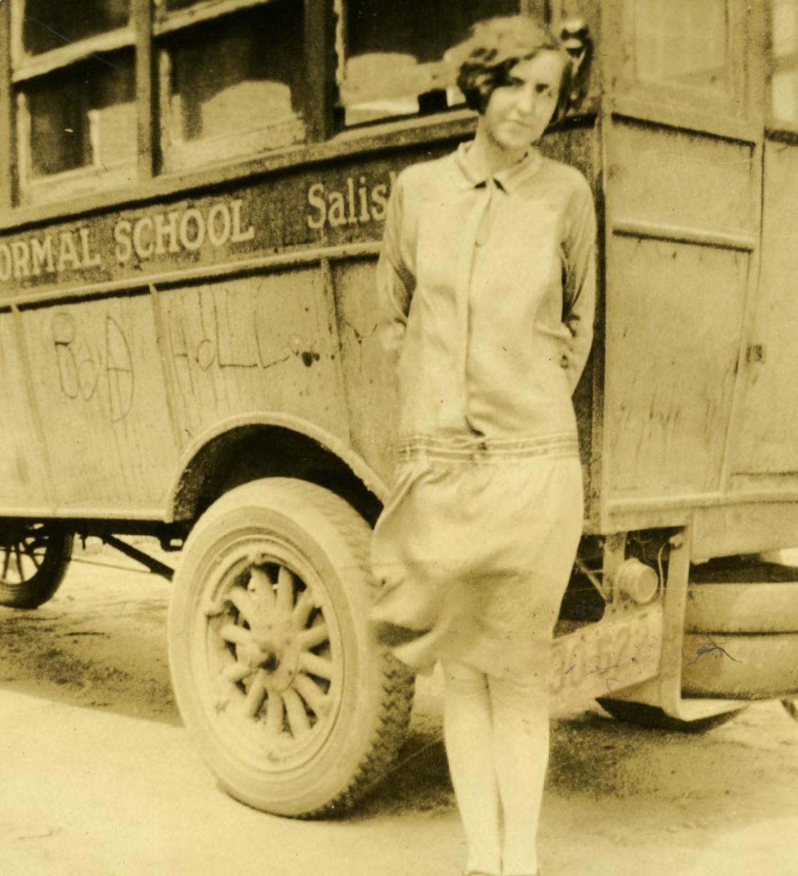 A sepia photo of a female student in front a Salisbury Normal School bus.