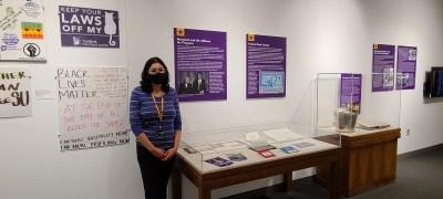 Sandra Zelaya in front of part of the Voices and Votes exhibit